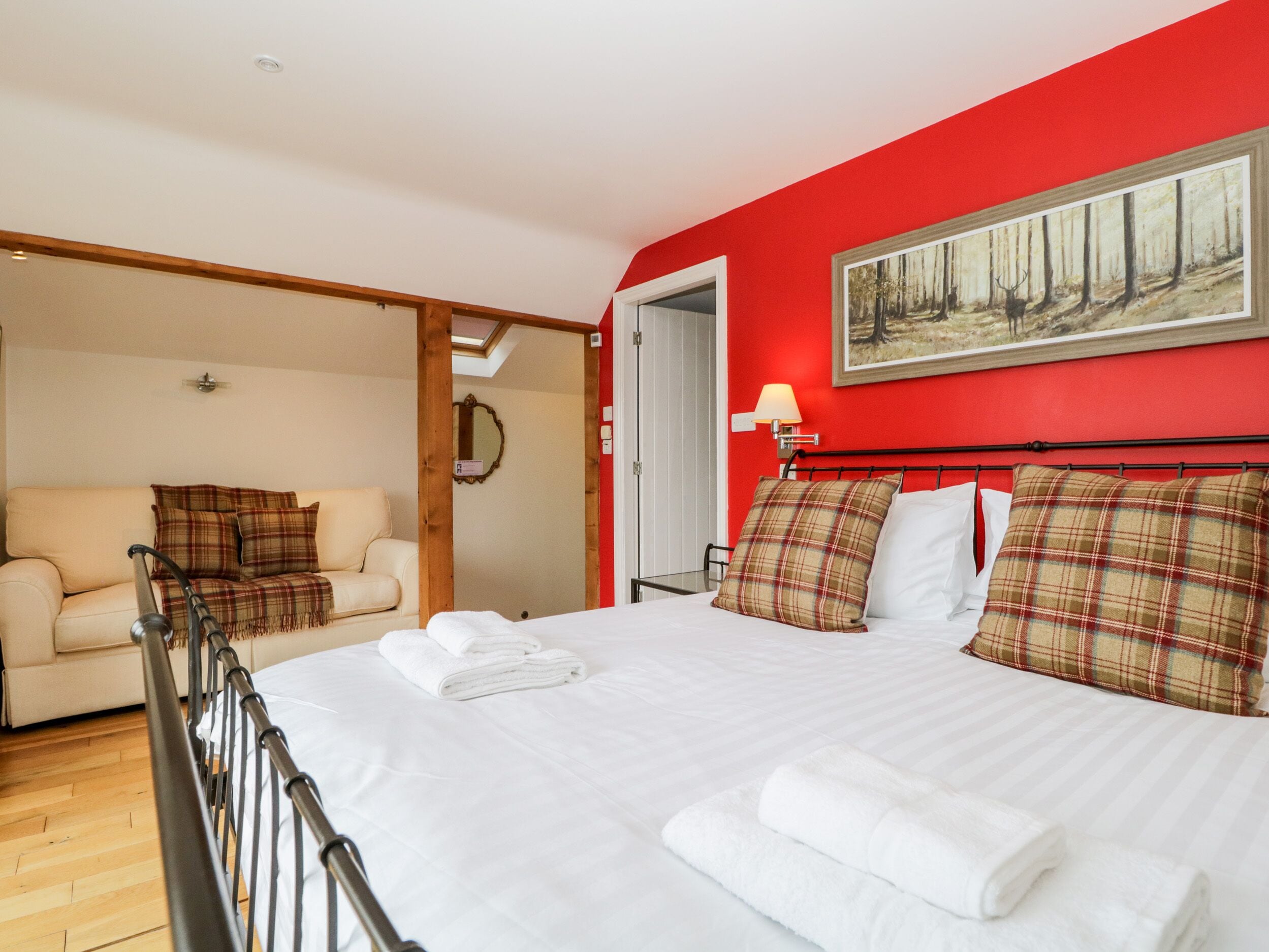 A bedroom with a bed, a sofa, a painting, and a lamp.