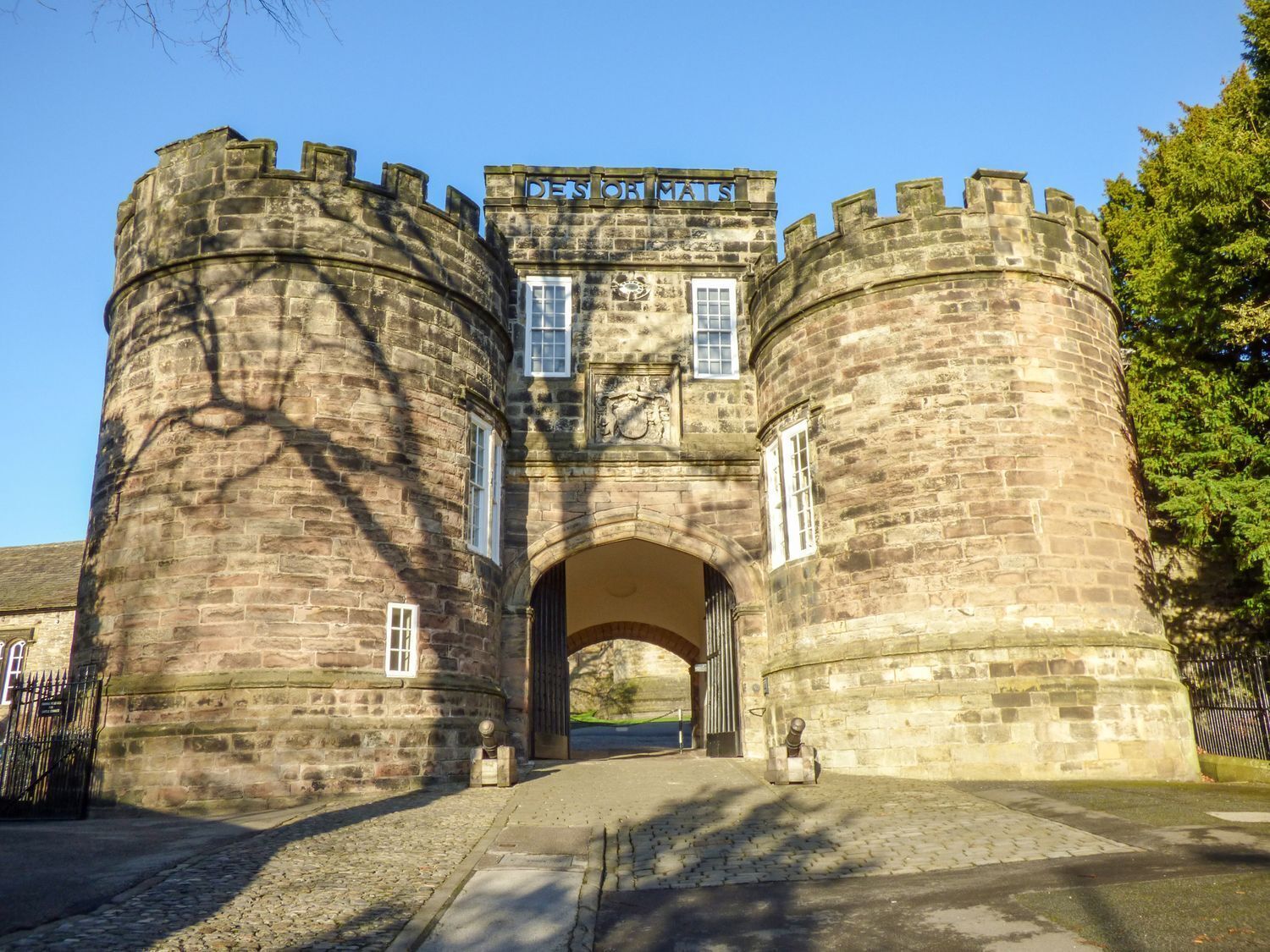 A historic stone building with a central archway and two round towers, labeled "DES ORMATS".