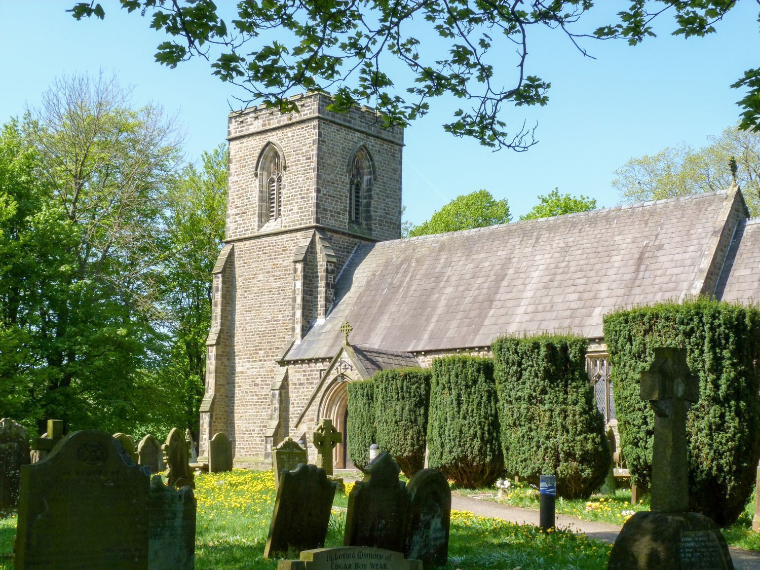 Une église dotée d’un clocher et d’un cimetière où se trouvent des pierres tombales.
