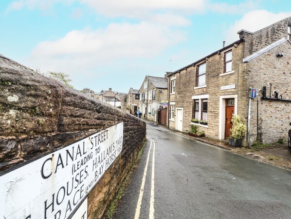 Une rue étroite bordée d’immeubles en pierre, une enseigne indiquant la rue Canal et une autre annonçant la vente d’un bien immobilier.