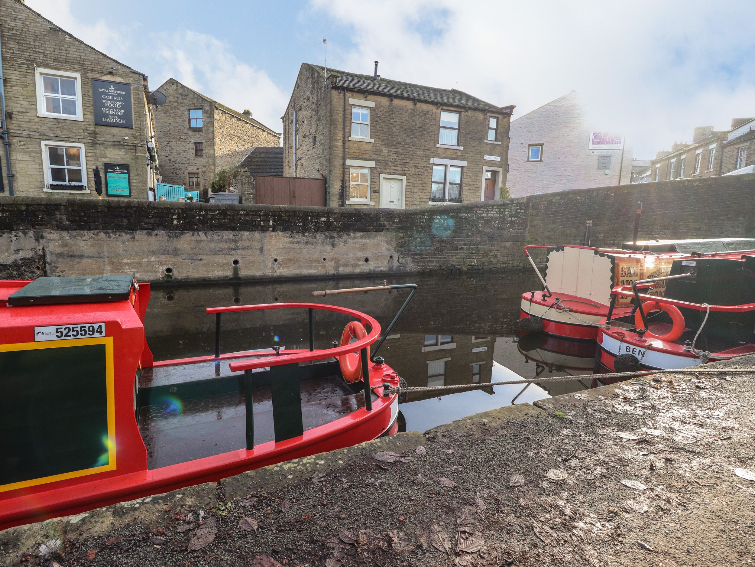 A canal with boats docked, stone buildings, and a clear sky.