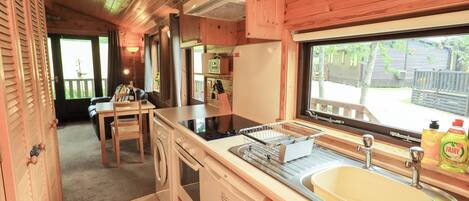 Une cuisine compacte dotée de meubles en bois, d’un évier, d’une cuisinière et d’un coin repas avec une table et des chaises.