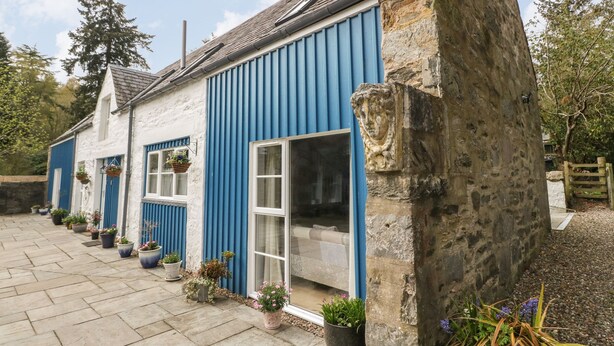 Un bâtiment traditionnel en pierre, avec une façade bleue et des éléments décoratifs blancs.