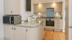 A modern kitchen with white cabinets, a built-in microwave, a Bosch oven, and a granite countertop. - Puccini (Pitlochry)