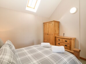 Un dormitorio con cama, armario de madera y tragaluz.