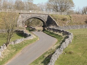 Un puente de piedra sobre un camino sinuoso en un entorno rural.