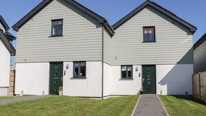 A two-story residential building with a symmetrical facade, green doors, and a central entrance. - 3 Parc Delfryn (Brynteg)
