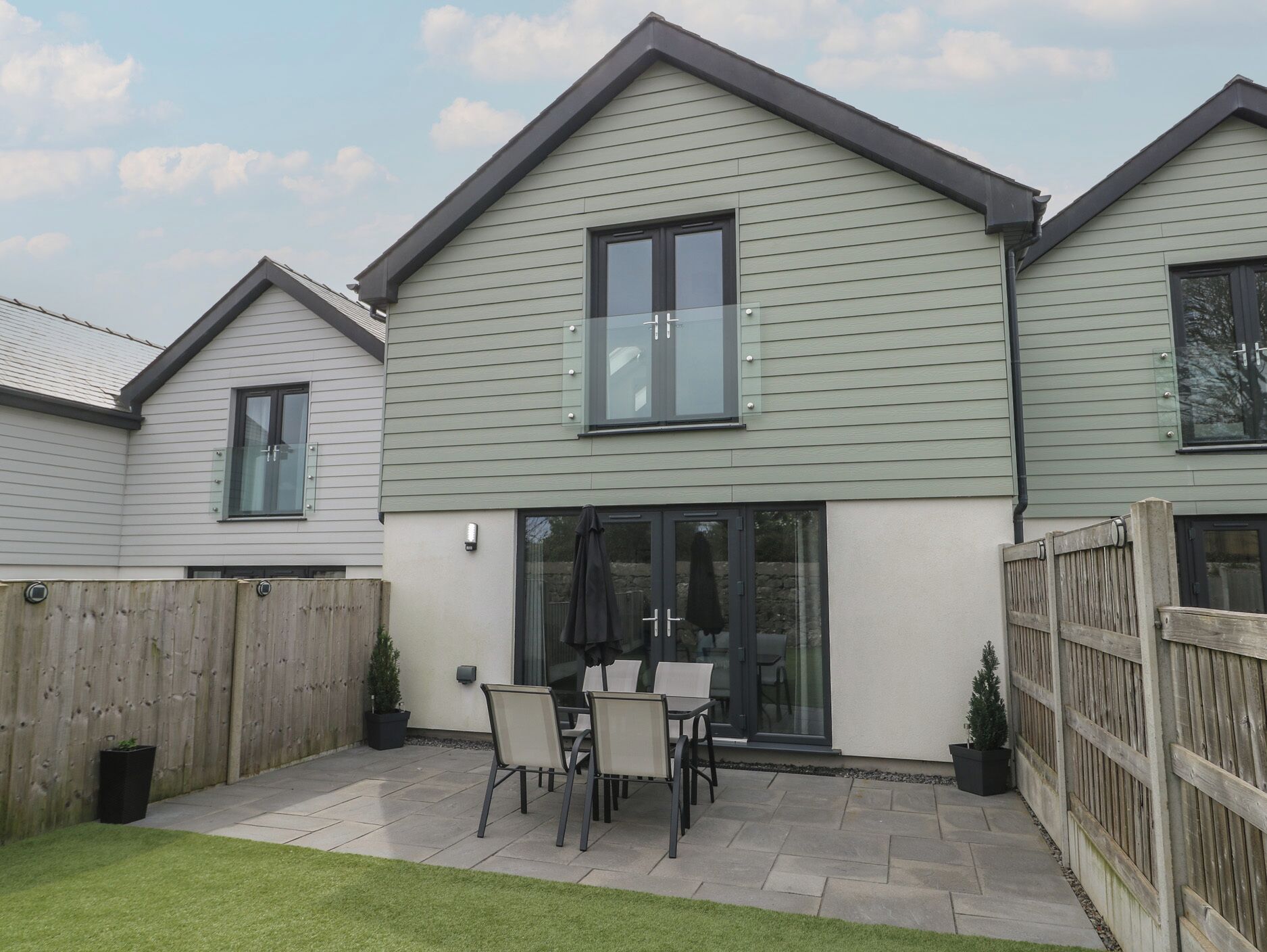 A two-story house with a patio area featuring a table and chairs.