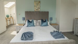 A bedroom with a bed, two bedside tables, a nightstand, a desk, and a chair. - 3 Parc Delfryn (Brynteg)