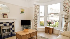 Una sala de estar con chimenea, televisor, muebles de madera y ventanas amplias.