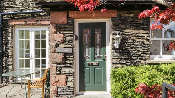 Un edificio de piedra con una puerta verde, un letrero que dice "SILVERTHWAITE" y una mesa con sillas afuera.