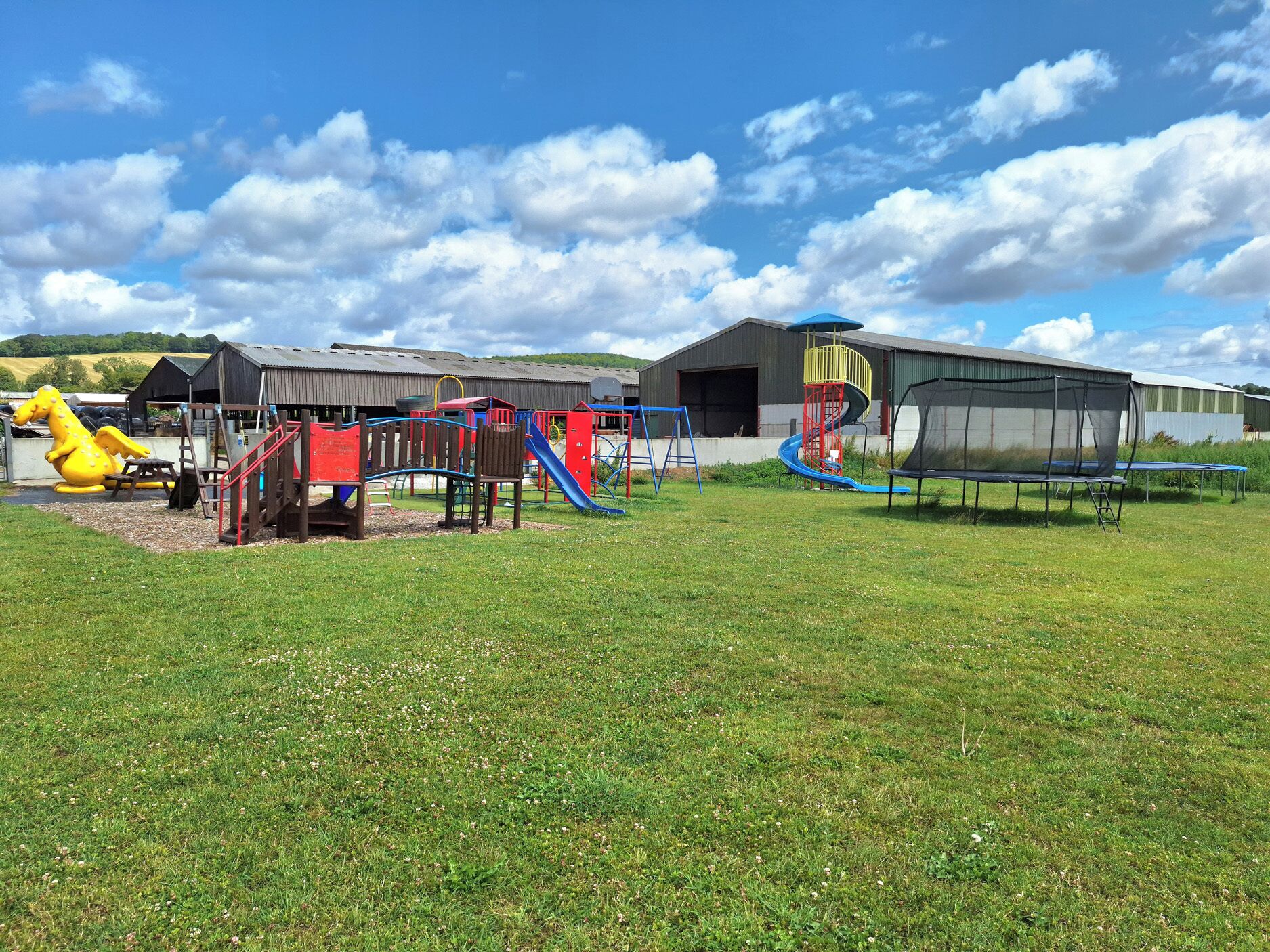 A playground with various play structures, including slides and climbing areas, in front of a building with a large garage door.