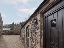 Un edificio de piedra con una puerta de madera oscura y un letrero que dice "The 6th Cumbrian".