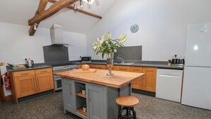 Una cocina moderna con armarios grises, una isla de madera y un lavavajillas integrado.