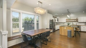 A modern kitchen with a wooden dining table, black chairs, and a chandelier. - Locust Estates Luxury Home – Downtown Windsor (Windsor)
