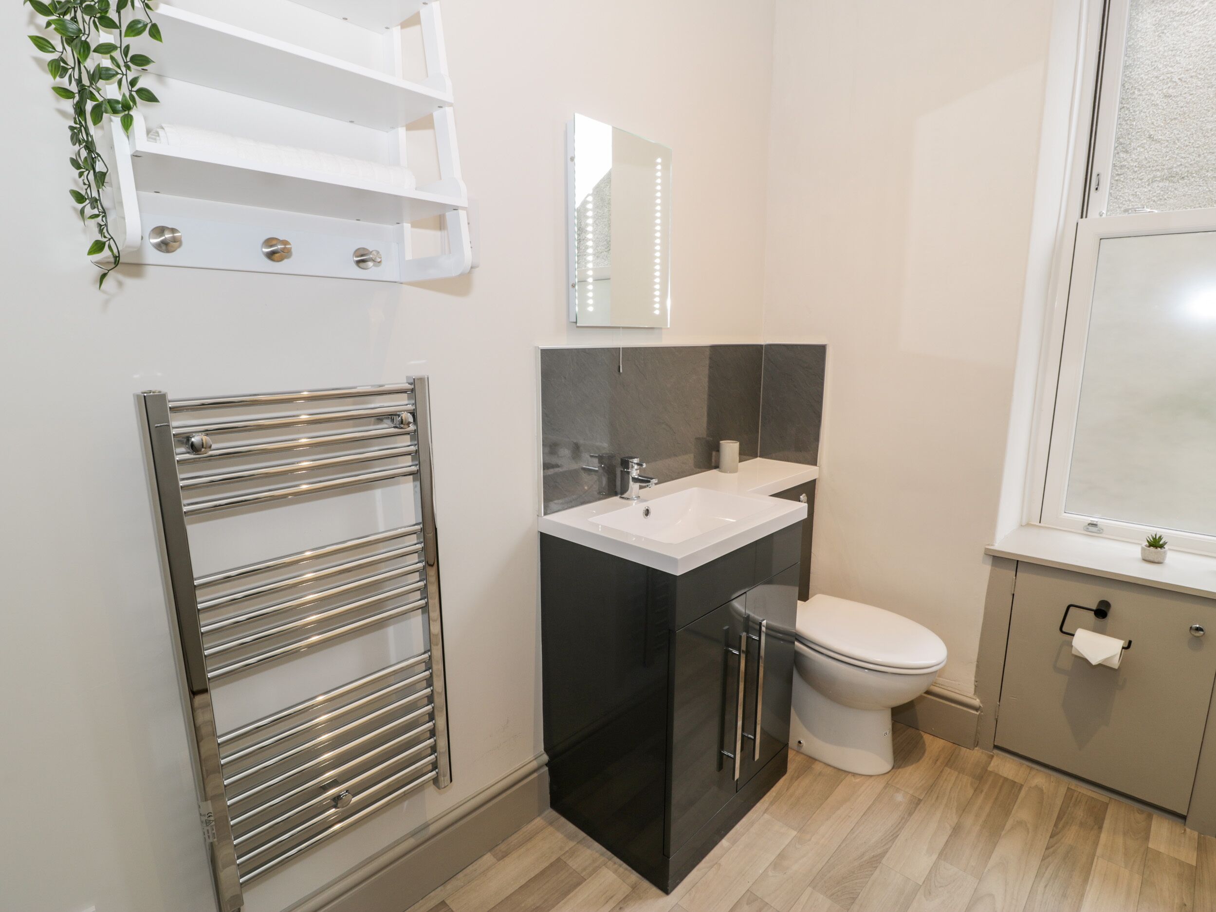 Un baño moderno con lavamanos integrado, inodoro y perchero para toallas.