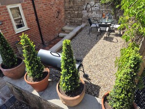 Une terrasse agrémentée de plantes en pot, d’un barbecue et de mobilier d’extérieur.