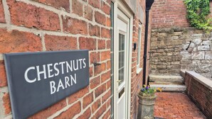 Un muro de ladrillo con un letrero que dice 'CHESTNUTS BARN' y una puerta.