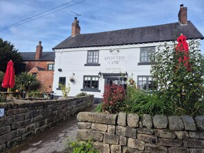 Un edificio blanco tradicional con un cartel que dice 'The Spotted Cow Freehouse'.
