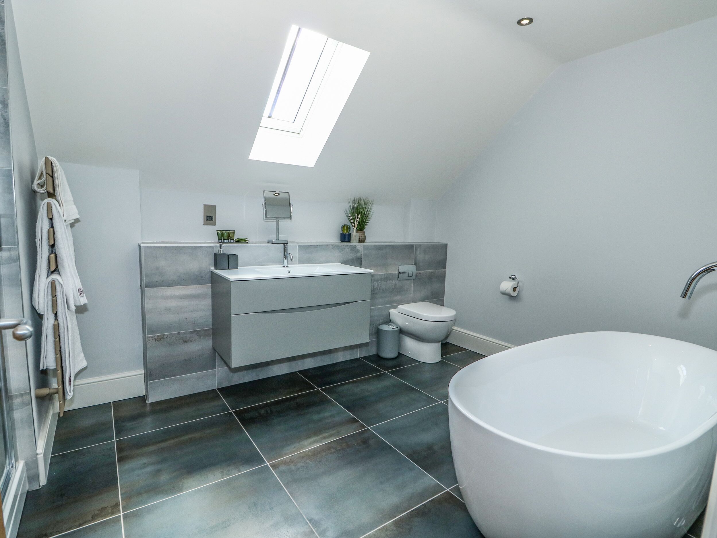 A modern bathroom with a freestanding bathtub, a vanity with a mirror, and a toilet.