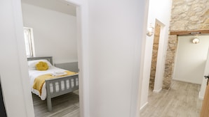 A bedroom with a bed, a radiator, and a stone wall.
