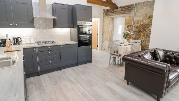 A modern kitchen with grey cabinets, a central island, and a dining area with a table and chairs.