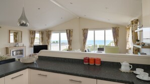 Une cuisine dotée d’une grande fenêtre, d’une cheminée et offrant une vue sur la mer.