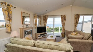 Un salon avec une cheminée, un canapé, une télévision et une vue sur la mer.