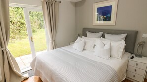 Une chambre à coucher avec un grand lit, une table de chevet avec une lampe, et une vue sur l’extérieur grâce à une porte coulissante.
