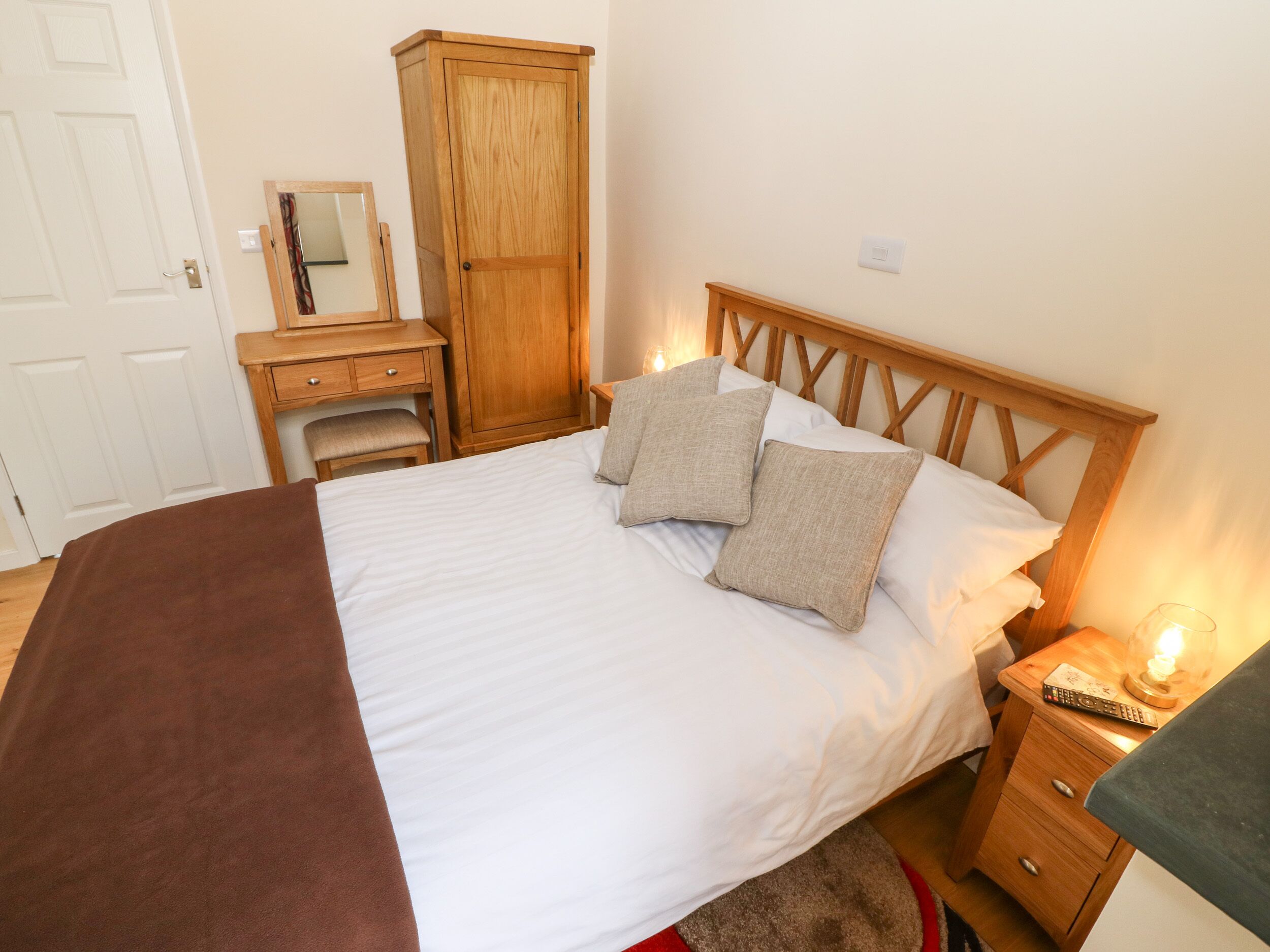 Une chambre bien rangée, avec un lit, des tables de chevet, une armoire et un bureau avec une chaise.