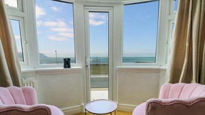 Una habitación con dos sillas rosadas frente a un ventanal que da al mar.