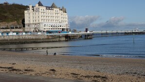 Un hotel grande con varios pisos y un letrero llamativo, ubicado frente a un muelle que se adentra en el agua.