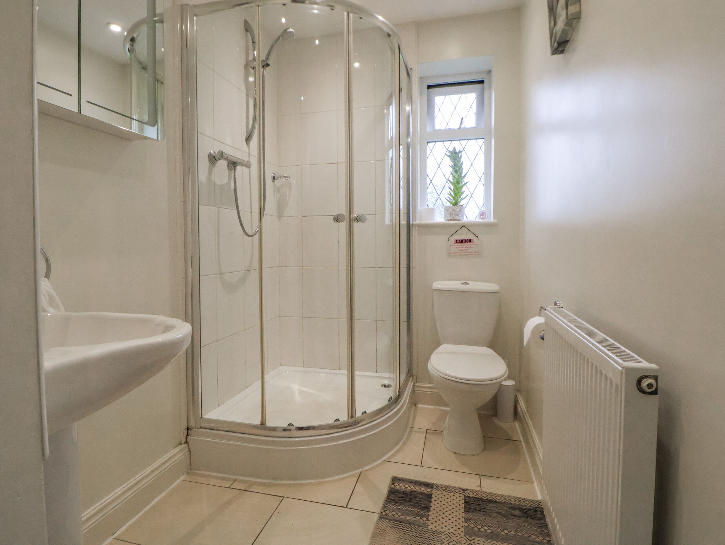 A modern bathroom with a glass-enclosed shower, a toilet, and a sink.
