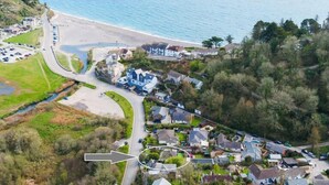 Luchtbeeld van een kustgebied met woonhuizen, een strand en een weg naar de zee.