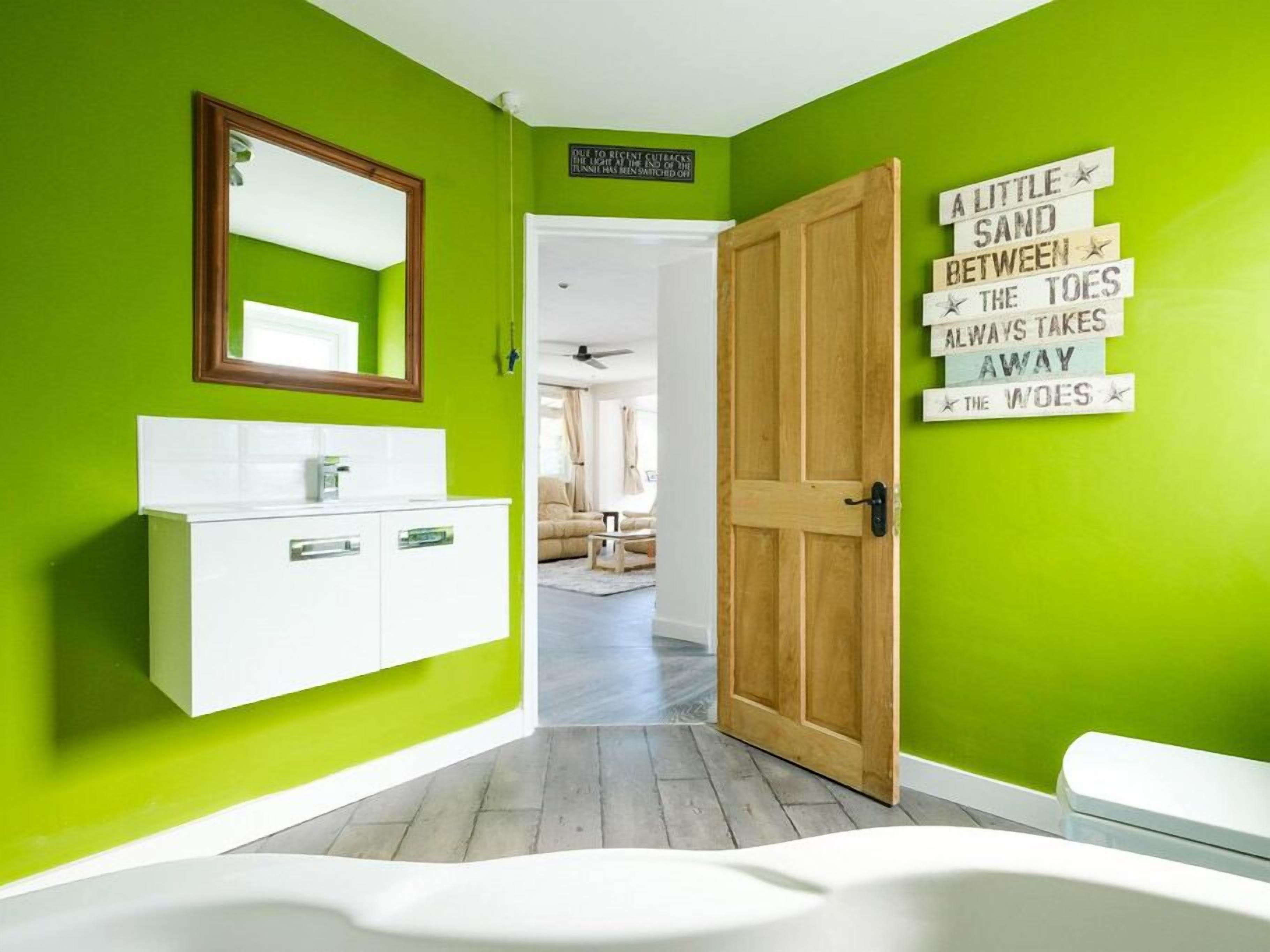 A bathroom with a white sink, a mirror, and a wooden door.