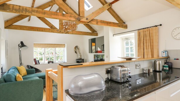 A kitchen with a wooden ceiling, a green sofa, a coffee machine, and a toaster. - Little Chygowlin (Truro)