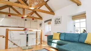 A spacious living area with a teal sofa, a colorful rug, and a wooden ceiling. - Little Chygowlin (Truro)