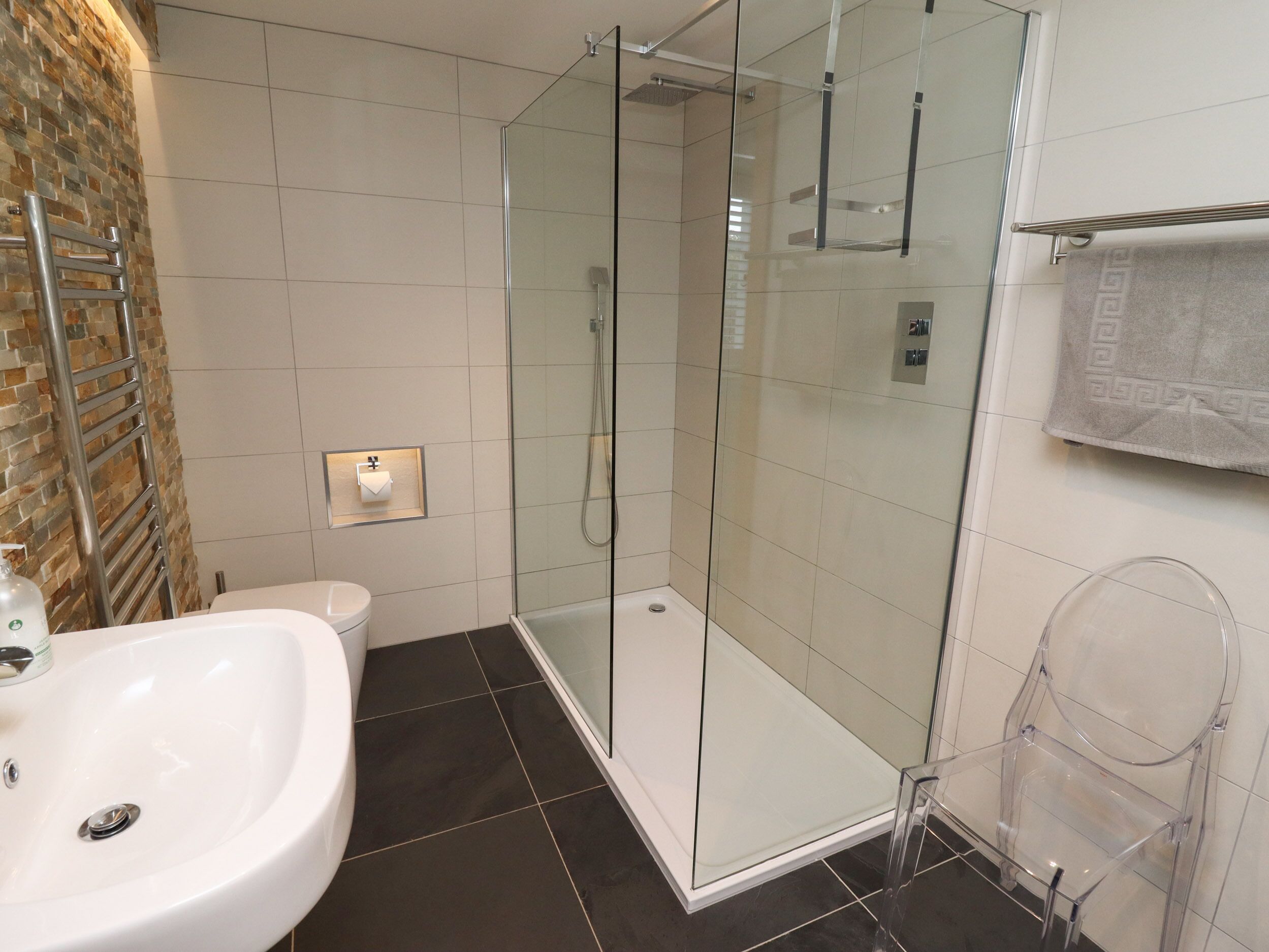 A modern bathroom with a glass-enclosed shower, a white sink, and a toilet.