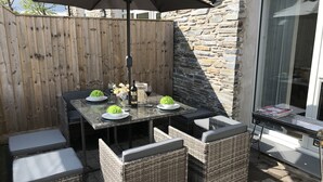 Un patio con una mesa, sillas y una sombrilla.