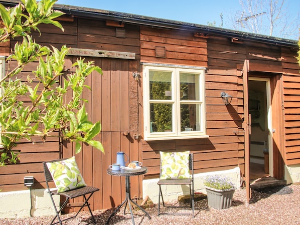A wooden building with a window, a door, and a small table with chairs.