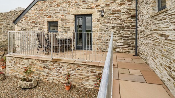 Un bâtiment en pierre doté d’un balcon, de plantes en pot et d’une terrasse carrelée.