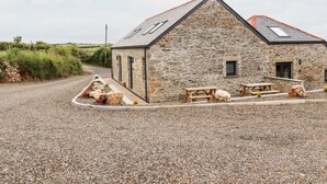 A stone building with a sloped roof, a gravel driveway, and a picnic table.