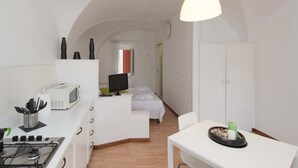 Eine kleine Küche mit Herd, Mikrowelle und einer Essecke mit Tisch und Stuhl.