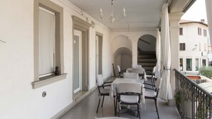 Ein Balkon mit Essbereich, inklusive Tischen und Stühlen, und Blick auf die Straße darunter.