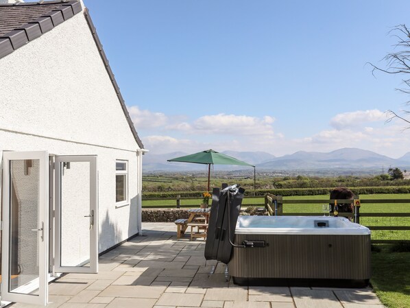 A patio area with a hot tub, outdoor seating, and a view of mountains.