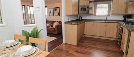 Une cuisine compacte avec des meubles en bois, un four encastré et un four à micro-ondes.