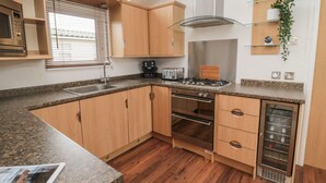 A modern kitchen with wooden cabinets, a built-in oven, a microwave, and a stainless steel range hood.