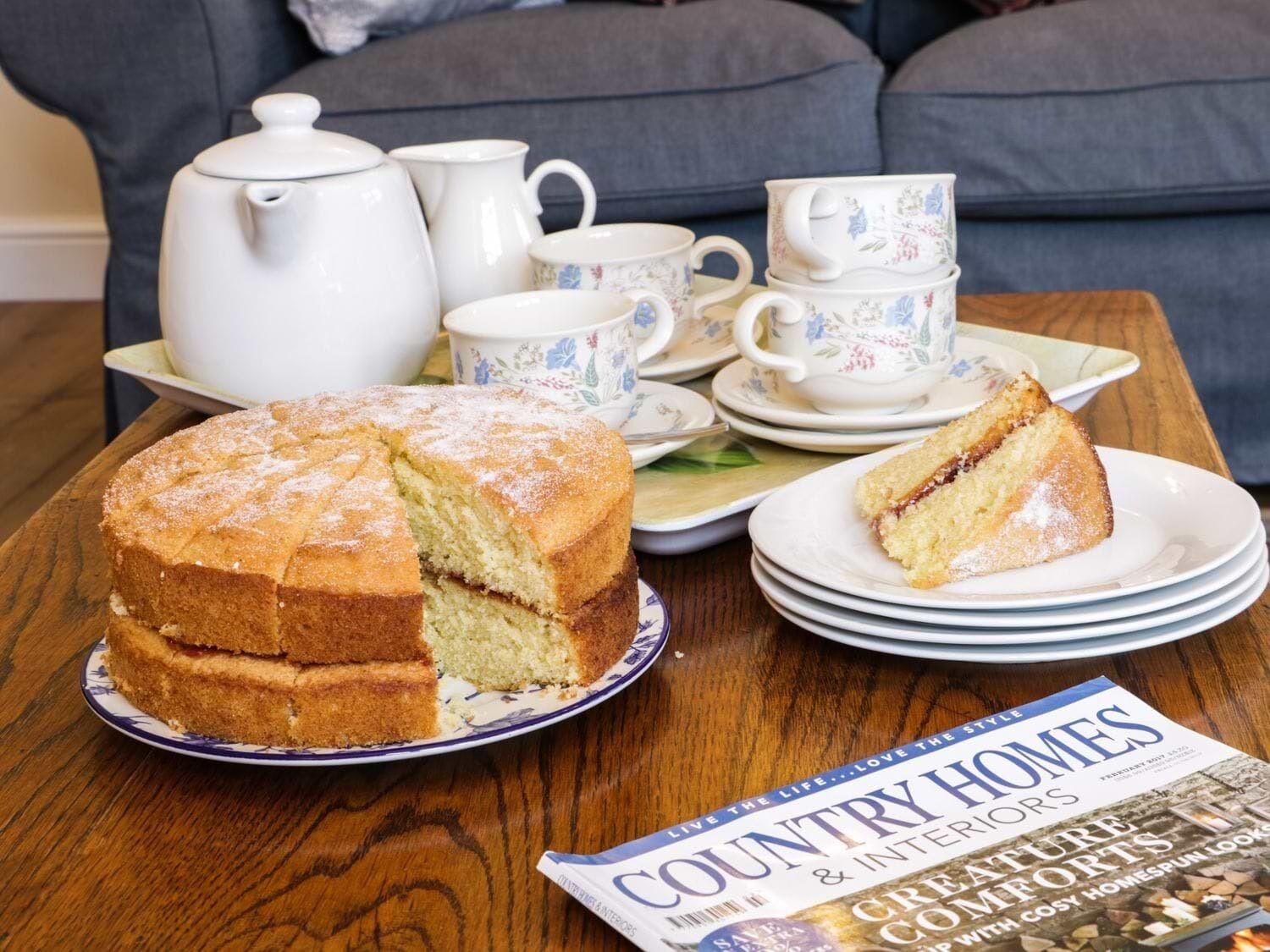 Una mesa con un pastel, un juego de té y una revista.