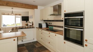 A kitchen with white cabinets, a double oven, a microwave, and a window with a view of the outdoors.