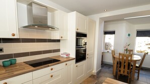 A modern kitchen with white cabinetry, a black countertop, and a built-in oven.